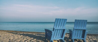 Two blue Adirondack chairs on the beach