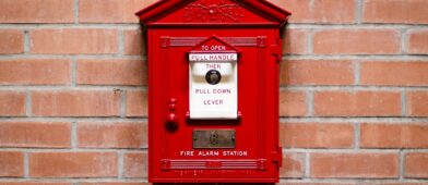 Red fire alarm on a brick wall