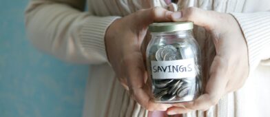 Retiree holding a jar of coins labeled "Savings"