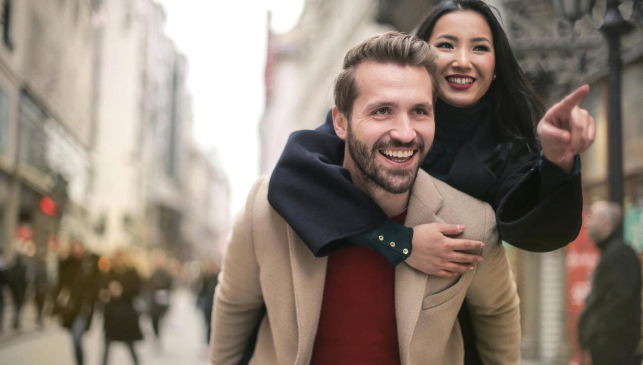 woman riding on a man's back and pointing ahead