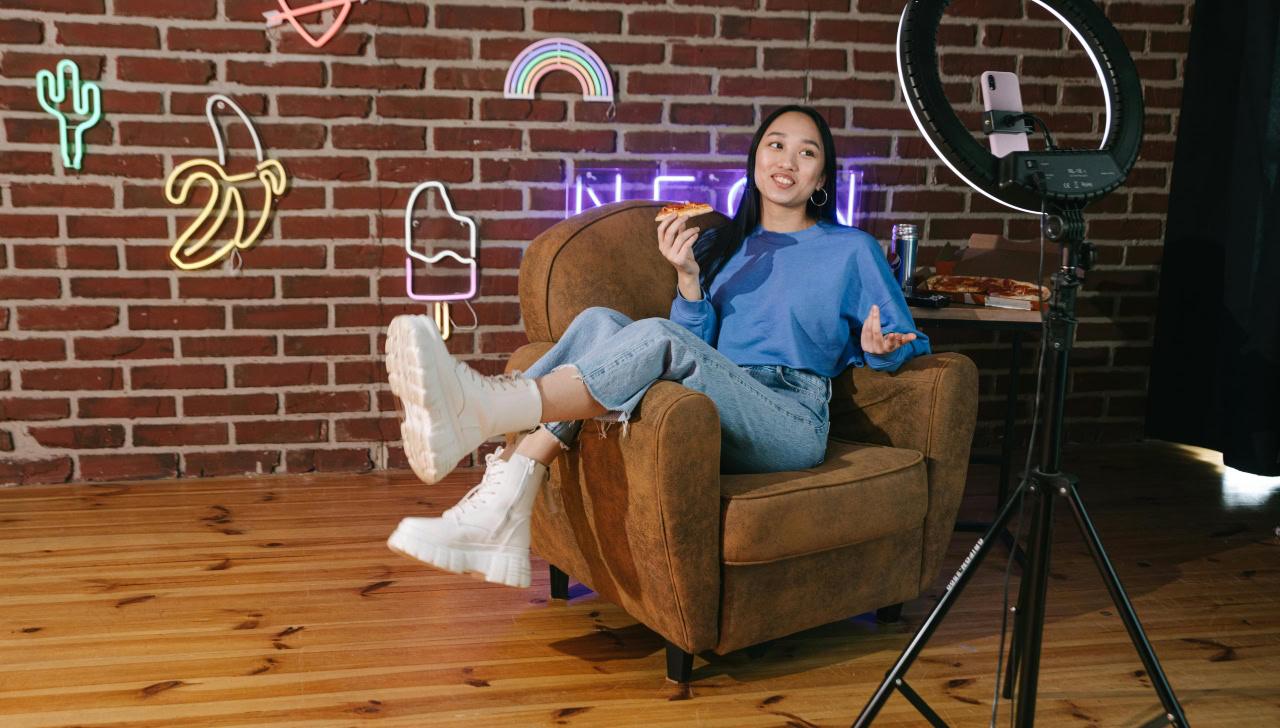 young woman sits in chair with trendy outfit in front of a camera