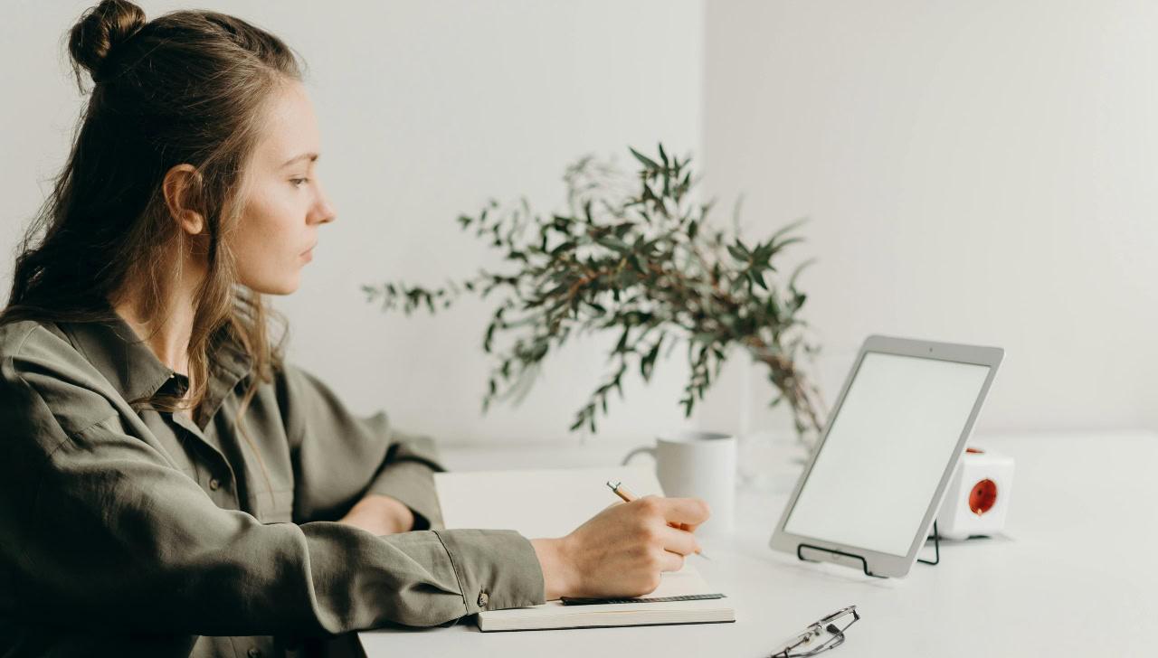 woman at desk looking at tablet