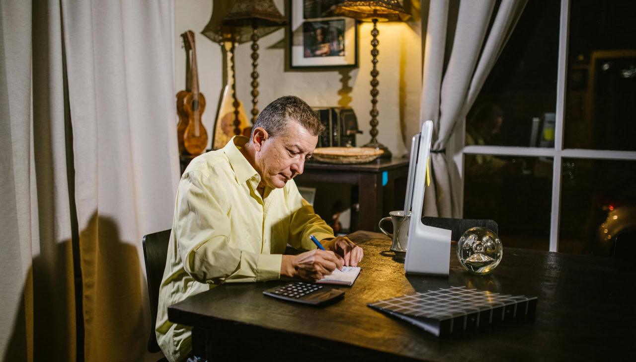 older man sitting at table working on paperwork