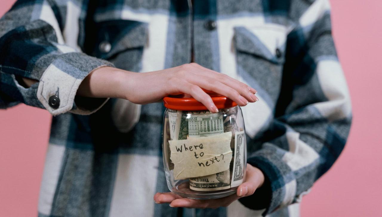 jar with money inside that says "where to next?" on it