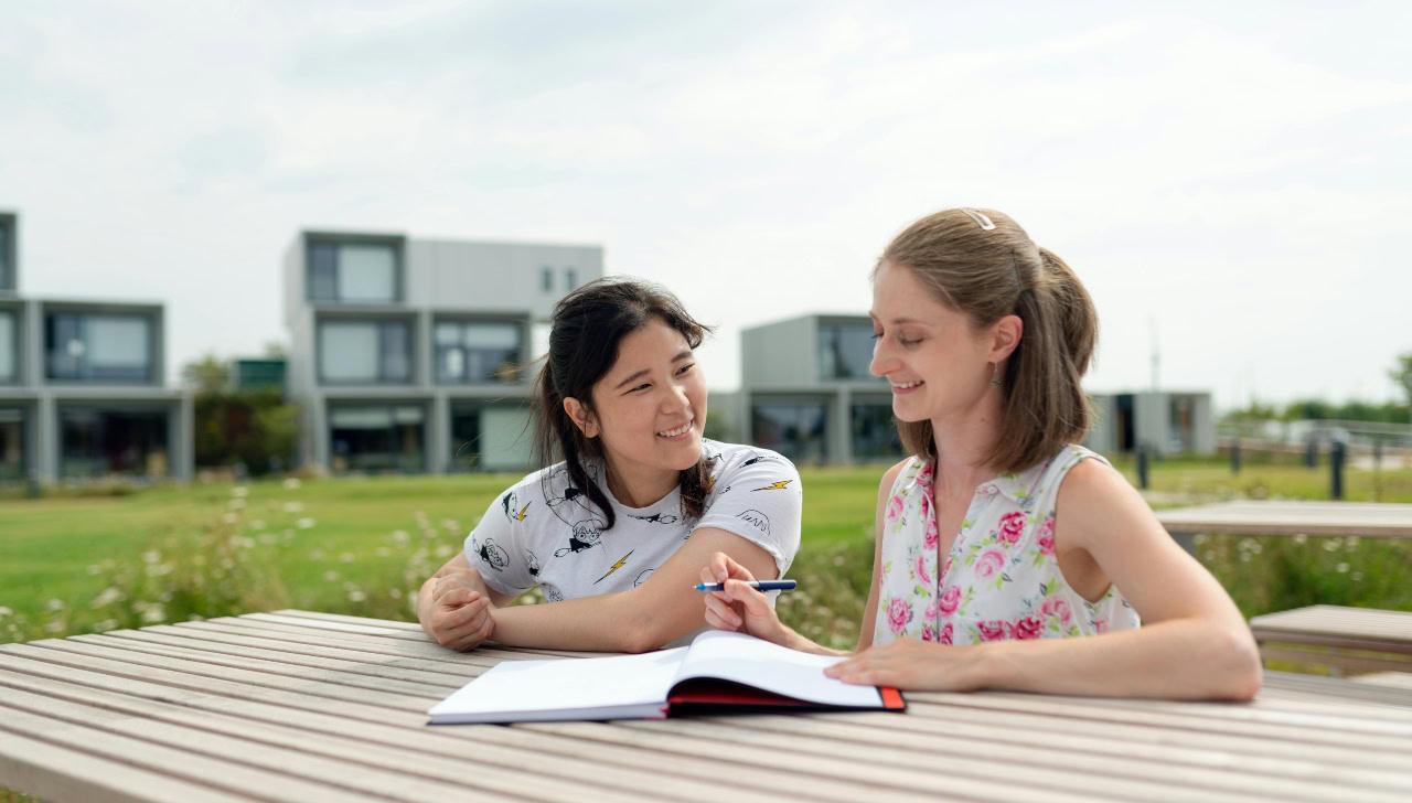woman looking at book with teenager